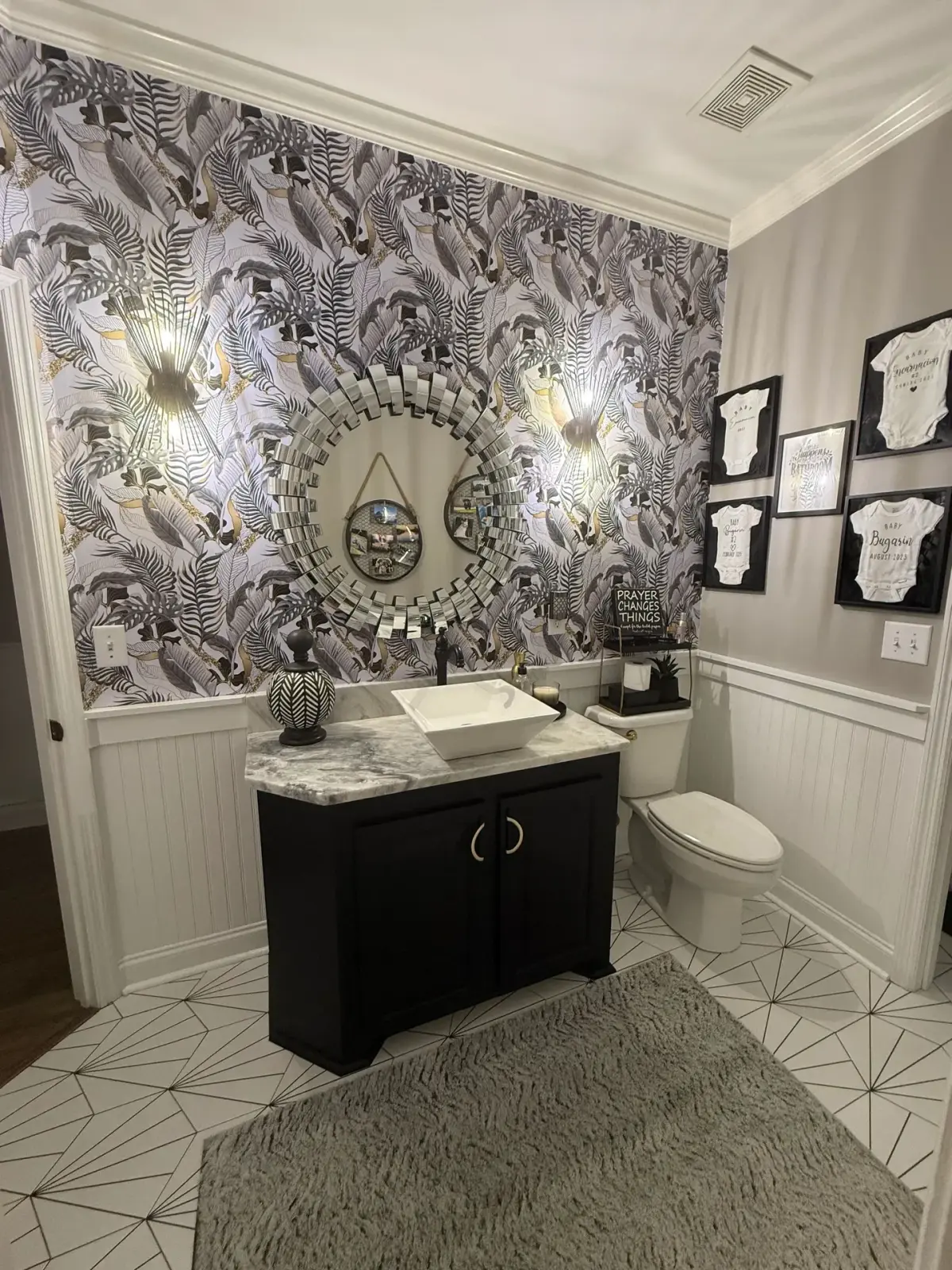 Bathroom with a dark vanity, vessel sink, patterned wallpaper and geometric floor tile