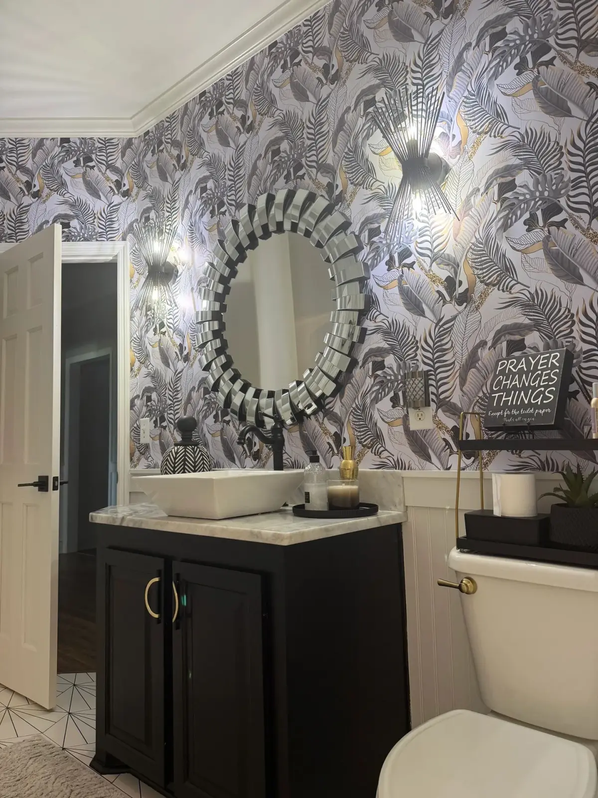Dark bathroom vanity and vessel basin beneath a round mosaic mirror