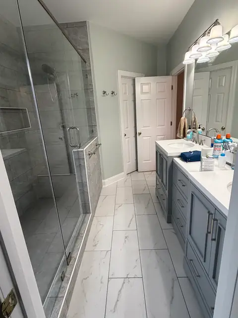 View down the bathroom with the glass shower on one side and the double vanity on the other, from Amanda Stevens’s Google review