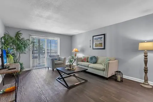 Apartment living room with wood-look flooring and gray walls, from Wanda Harland’s Google review