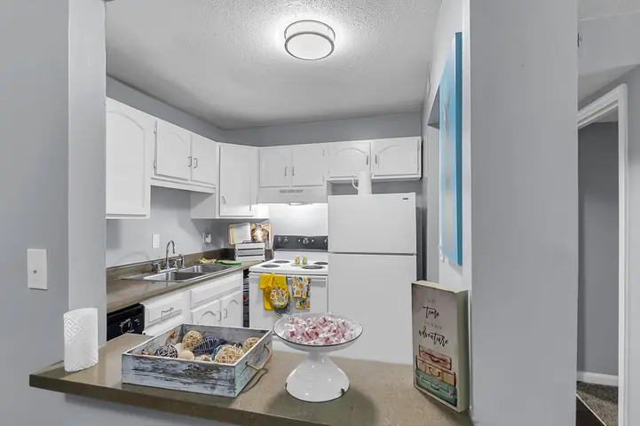 Apartment kitchen with white cabinets, seen from the breakfast bar, from Wanda Harland’s Google review